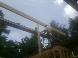 Carpenter setting a ridge beam over a new addition frame — Ice Dam Removal by Roofing Brothers in Moffit