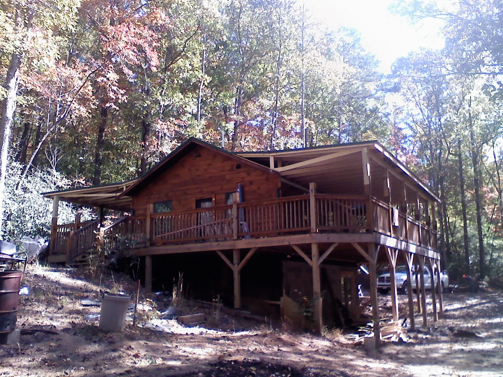 Log cabin with a wraparound porch and metal roof in the fall in Moffit