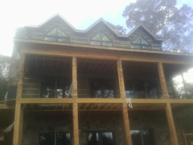 Dormers and porch framing on a large log home under construction — Roof Coating work by our crew in Moffit
