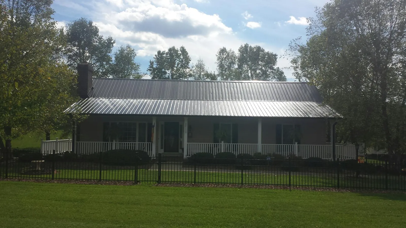 Gray metal roof on a brick ranch with a full width front porch — Gutter Guard Installation work by our crew in Moffit